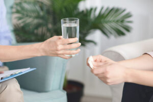 psychologist hand giving glass of water to patient