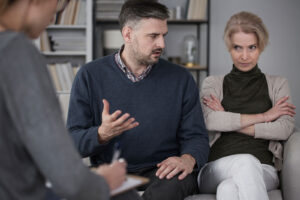 Husband talking to his wife with crossed arms on the addiction therapy